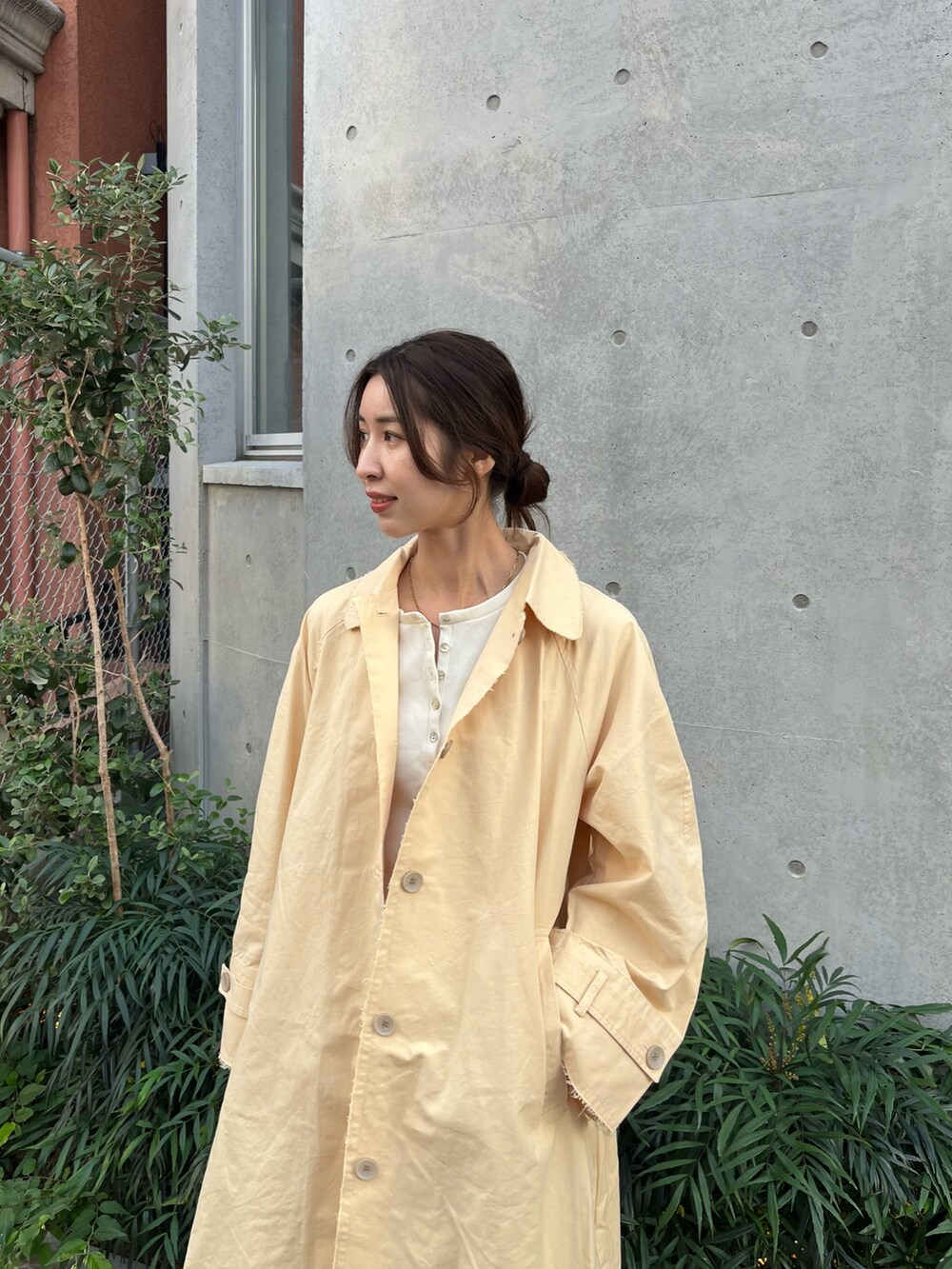 イエロー系のステンカラーコート、ホワイト系のTシャツ/カットソー、グレー系のその他パンツを着用したレディースの秋コーディネートの4枚目の写真