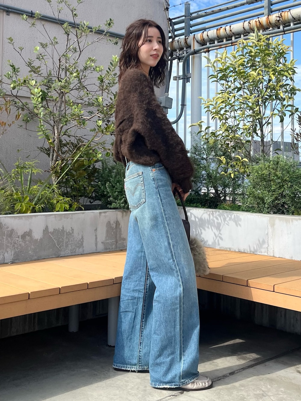 ブラウン系のニット/セーター、ブルー系のデニムパンツ、ブラウン系のハンドバッグを着用したレディースの秋コーディネートの2枚目の写真