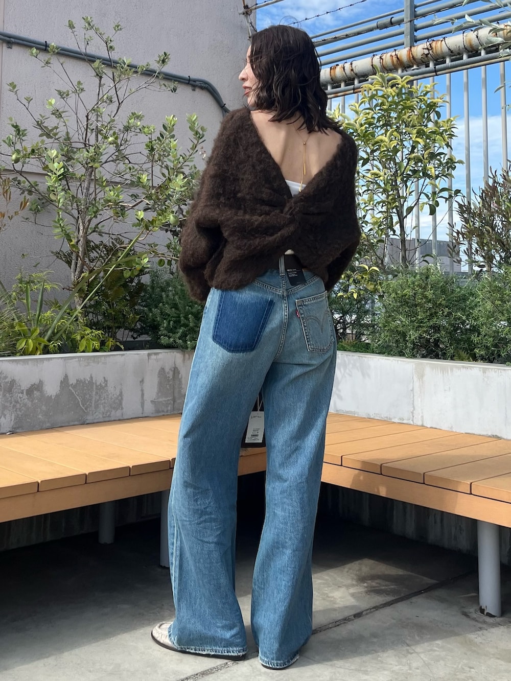 ブラウン系のニット/セーター、ブルー系のデニムパンツ、ブラウン系のハンドバッグを着用したレディースの秋コーディネートの3枚目の写真