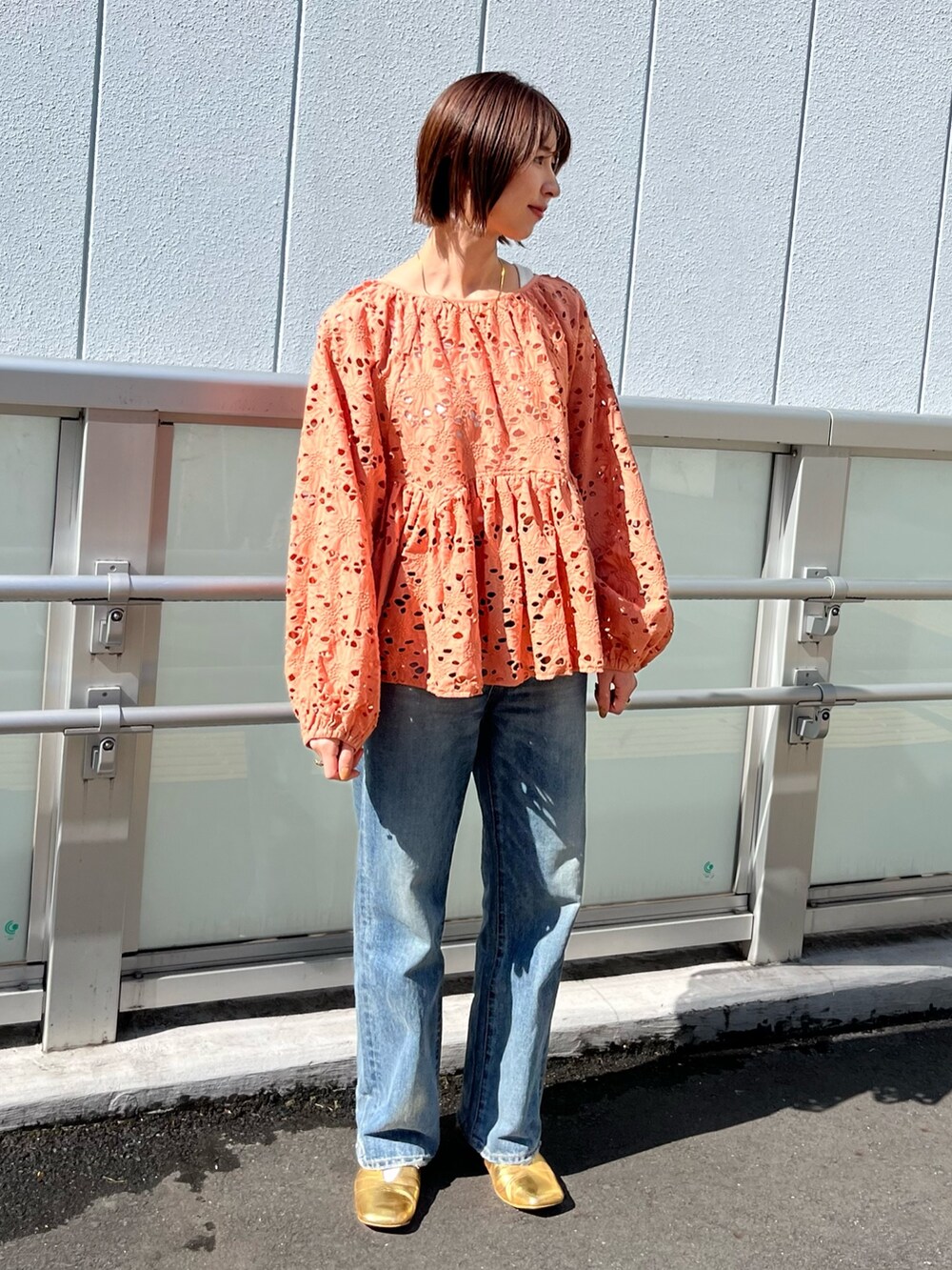 オレンジ系のシャツ/ブラウス、ブルー系のデニムパンツ、ゴールド系のパンプスを着用したレディースの冬コーディネートの2枚目の写真