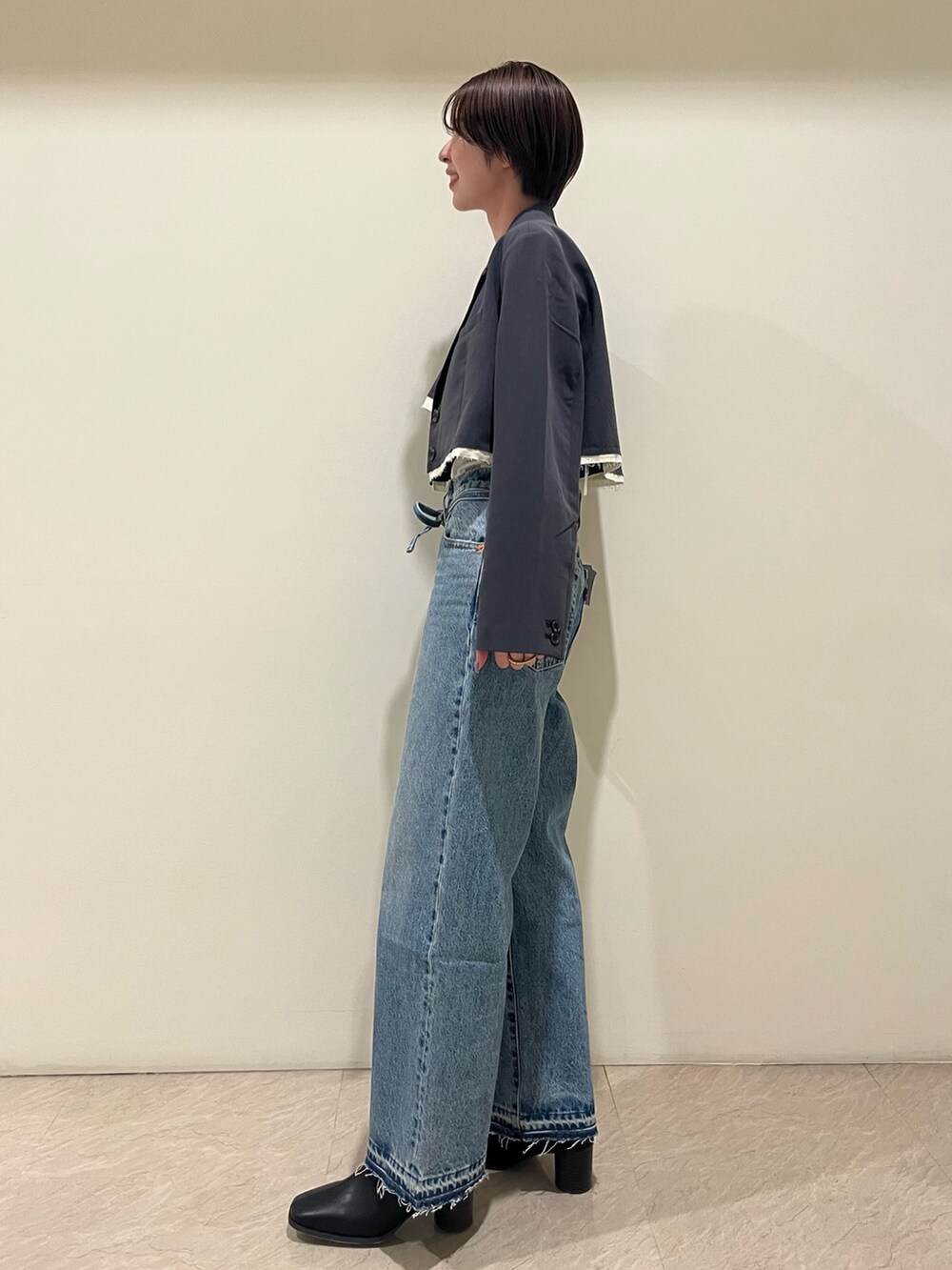 グレー系のテーラードジャケット、グレー系のキャミソール、ブルー系のデニムパンツを着用したレディースの夏コーディネートの2枚目の写真