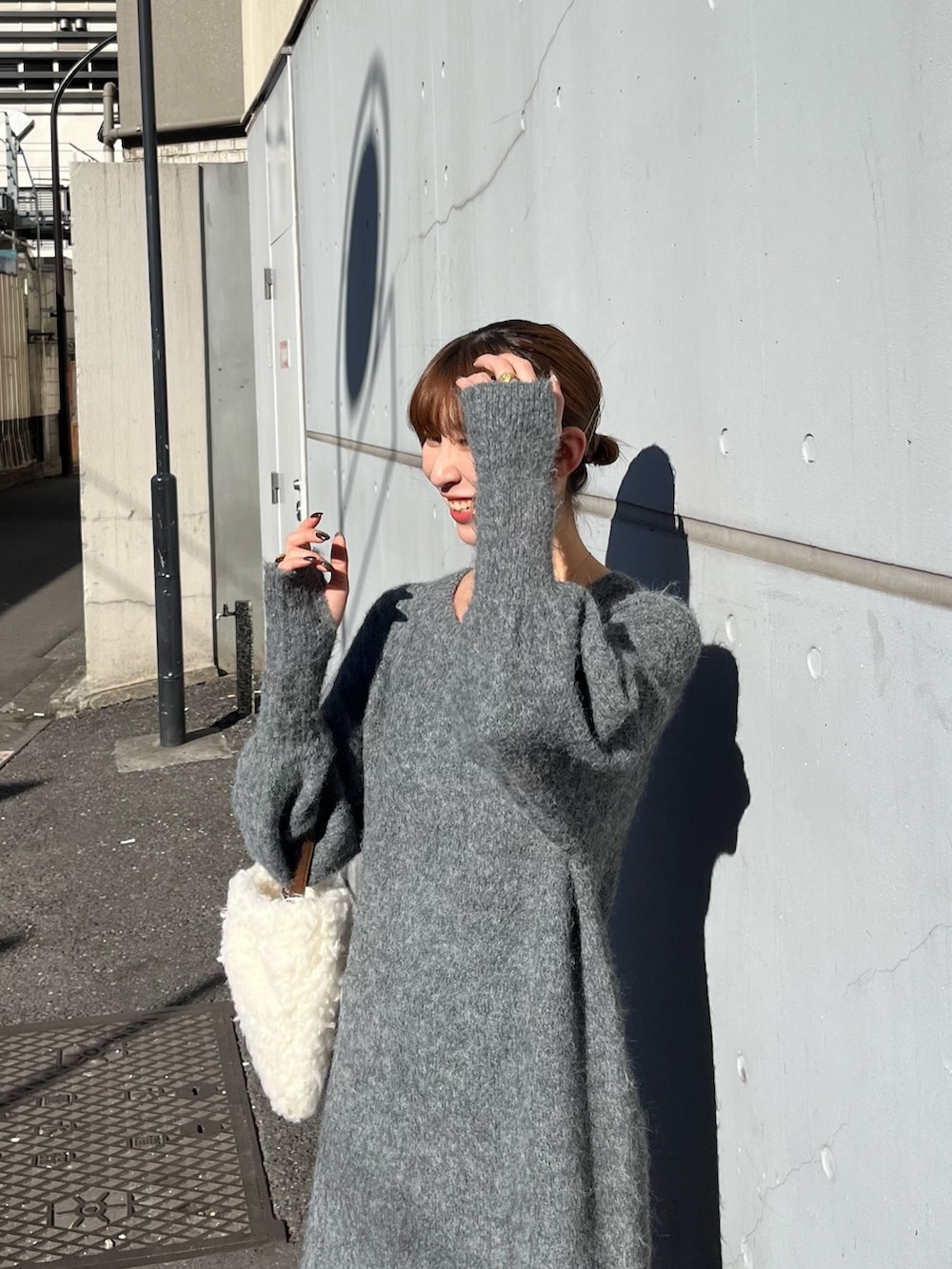 ホワイト系のハンドバッグ、グレー系のワンピースを着用したレディースの秋コーディネートの4枚目の写真