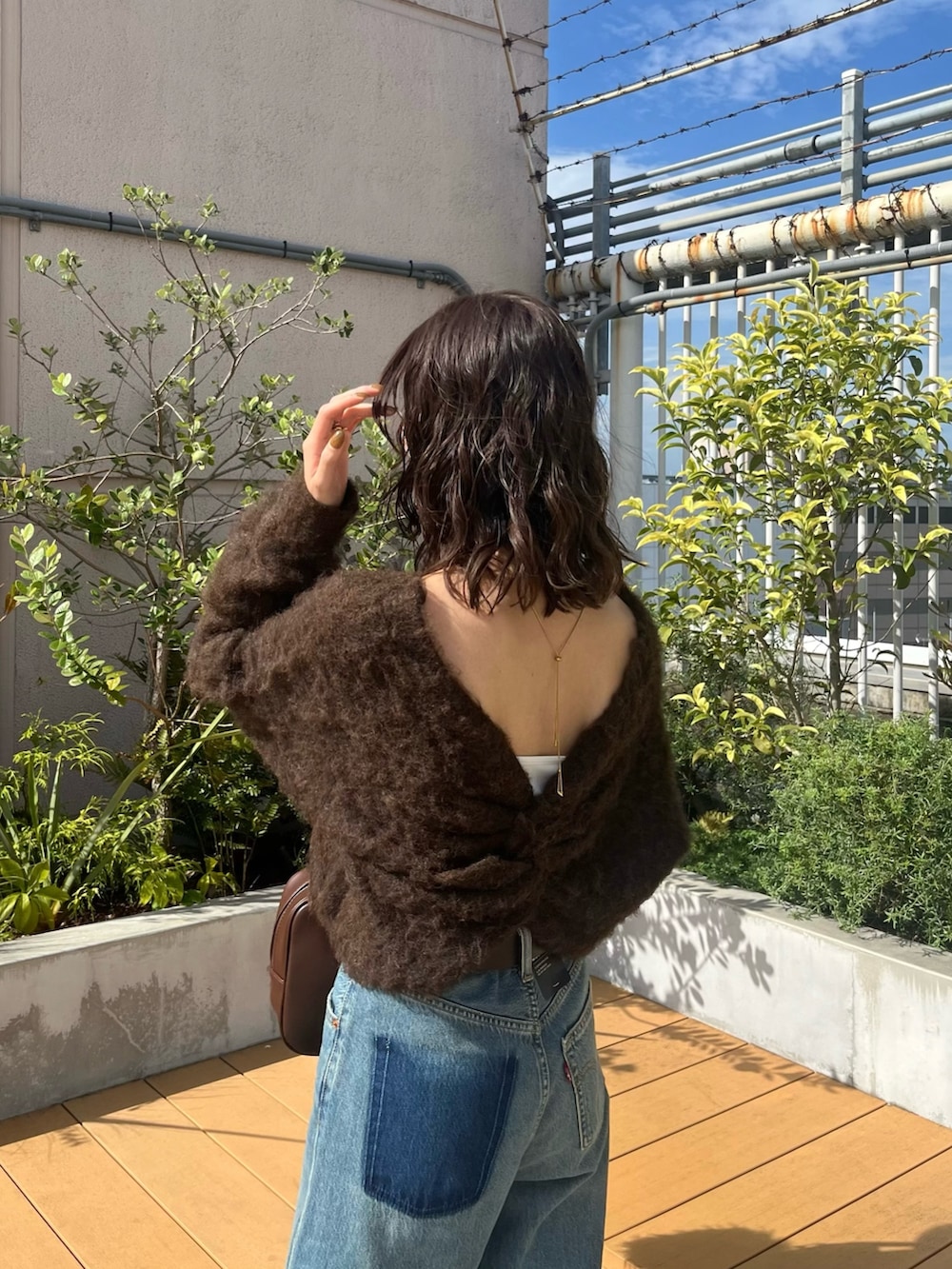 ブラウン系のニット/セーター、ブルー系のデニムパンツ、ブラウン系のハンドバッグを着用したレディースの秋コーディネートの5枚目の写真