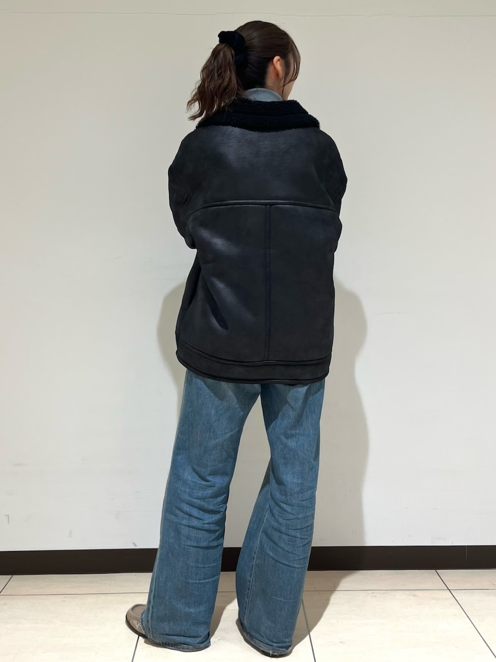 ブラック系のブルゾン、ブルー系のデニムパンツ、ベージュ系のローファーを着用したレディースの冬コーディネートの3枚目の写真