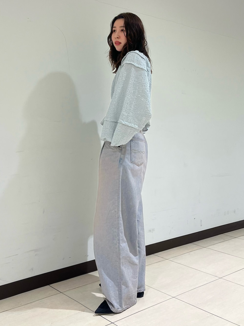 ブルー系のデニムパンツ、ブラック系のパンプスを着用したレディースの春コーディネートの2枚目の写真