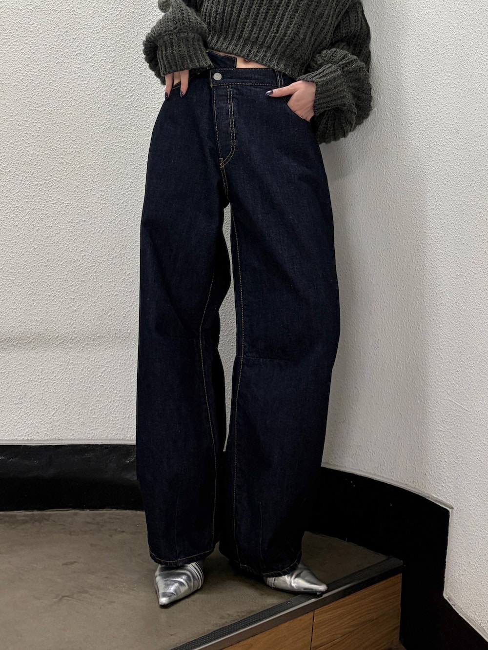 グレー系のニット/セーター、ブルー系のデニムパンツ、シルバー系のパンプスを着用したレディースの秋コーディネートの5枚目の写真