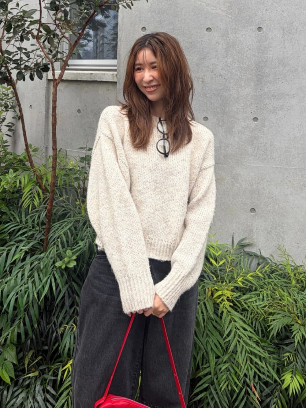 ホワイト系のニット/セーター、ブラック系のデニムパンツ、レッド系のハンドバッグを着用したレディースの秋コーディネートの4枚目の写真