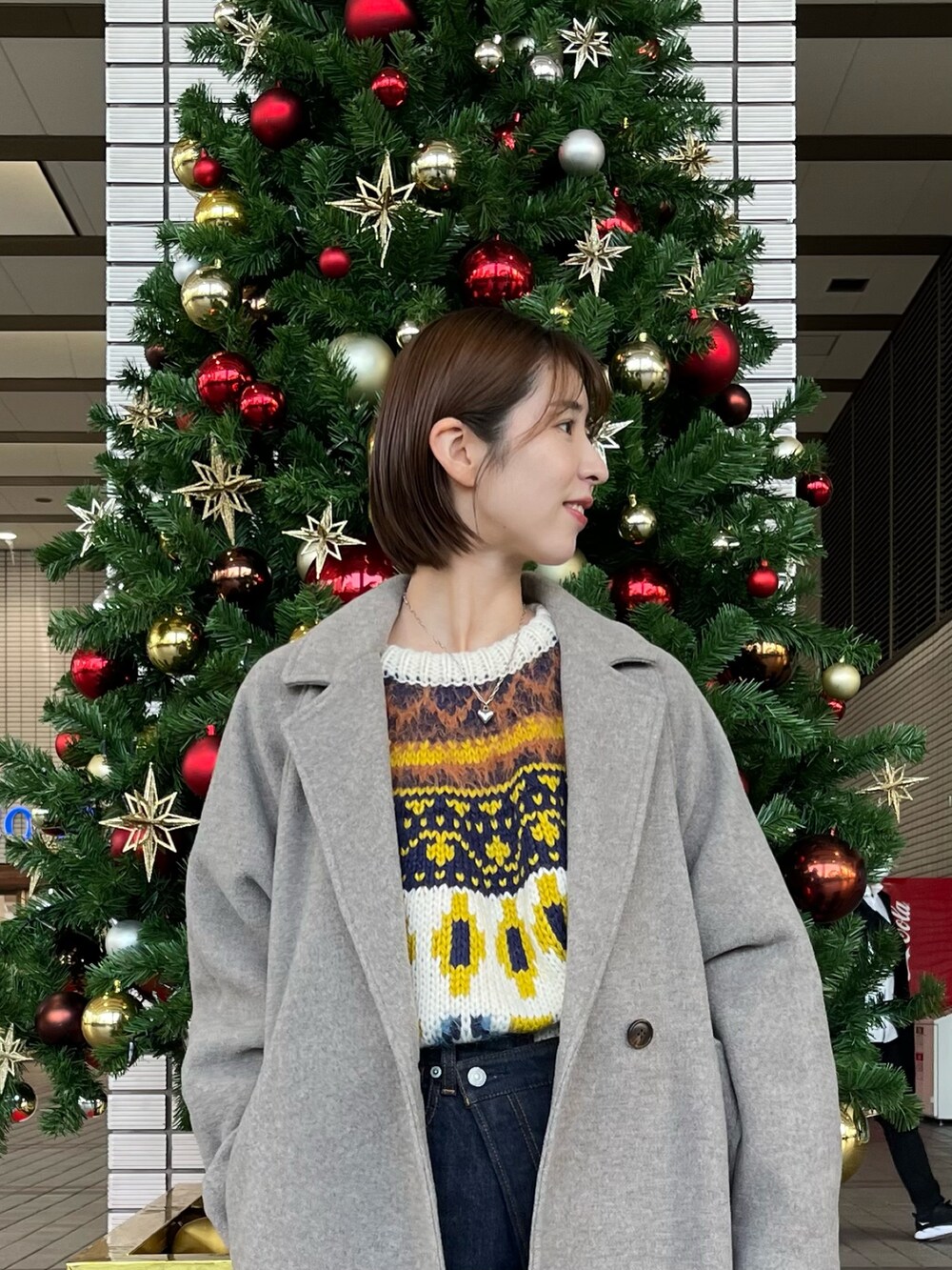 ホワイト系のニット/セーター、グレー系のチェスターコート、ブルー系のデニムパンツを着用したレディースの冬コーディネートの4枚目の写真