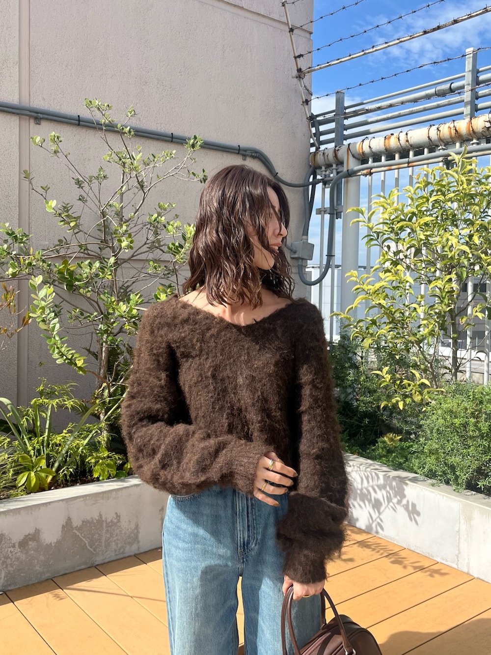 ブラウン系のニット/セーター、ブルー系のデニムパンツ、ブラウン系のハンドバッグを着用したレディースの秋コーディネートの4枚目の写真