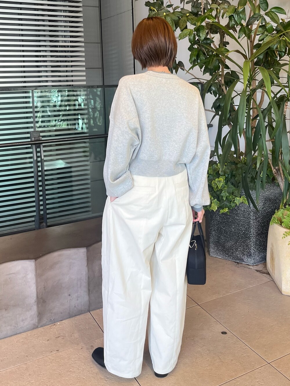 グレー系のニット/セーター、ホワイト系のチノパンツ、ブラック系のボストンバッグを着用したレディースの冬コーディネートの3枚目の写真