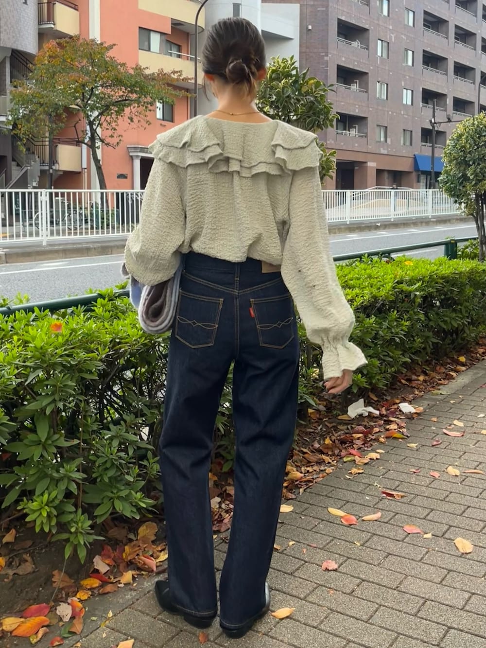 ブルー系のシャツ/ブラウス、グレー系のチェスターコート、ブルー系のデニムパンツを着用したレディースの秋コーディネートの6枚目の写真