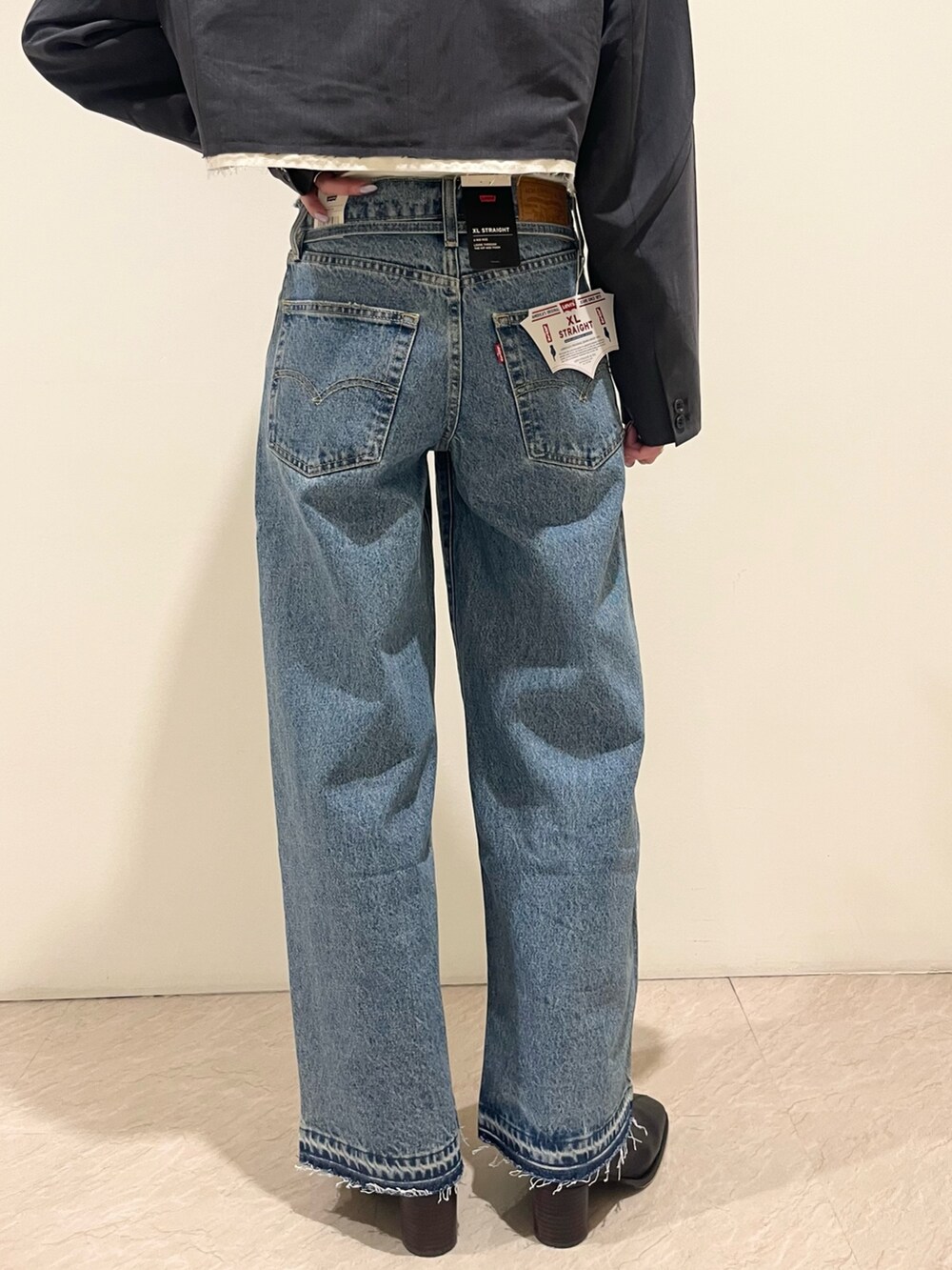 グレー系のテーラードジャケット、グレー系のキャミソール、ブルー系のデニムパンツを着用したレディースの夏コーディネートの6枚目の写真