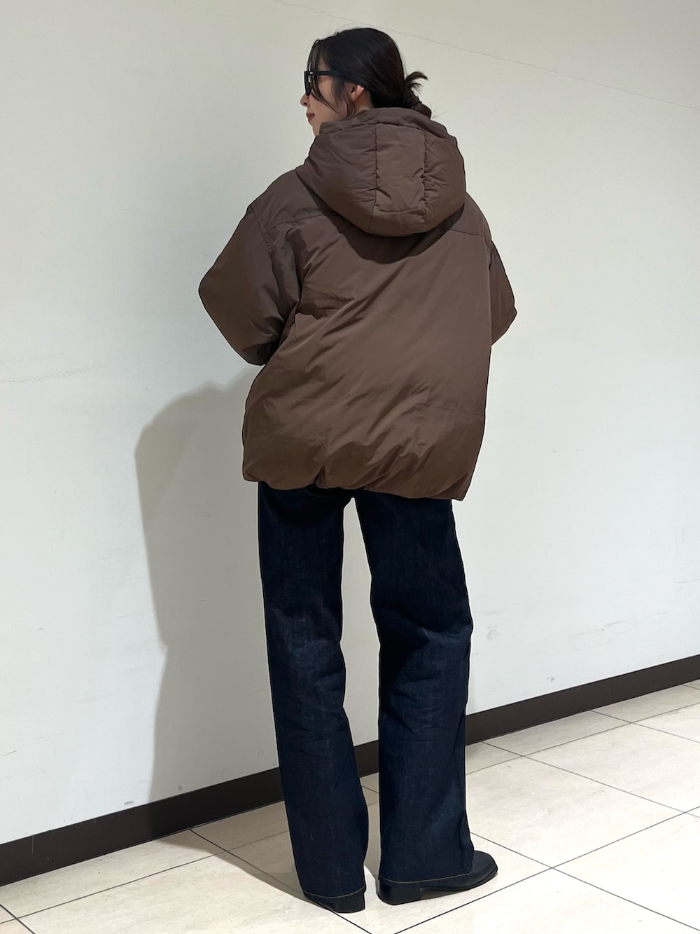ブラウン系のダウンジャケット/コート、ブルー系のデニムパンツ、ブラック系のサングラスを着用したレディースの冬コーディネートの3枚目の写真
