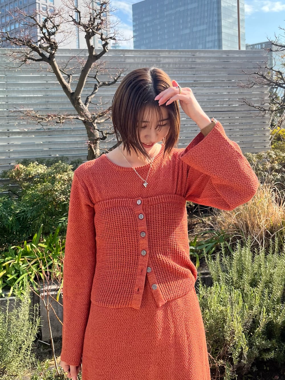 オレンジ系のワンピース、ブルー系のデニムパンツを着用したレディースの冬コーディネートの4枚目の写真