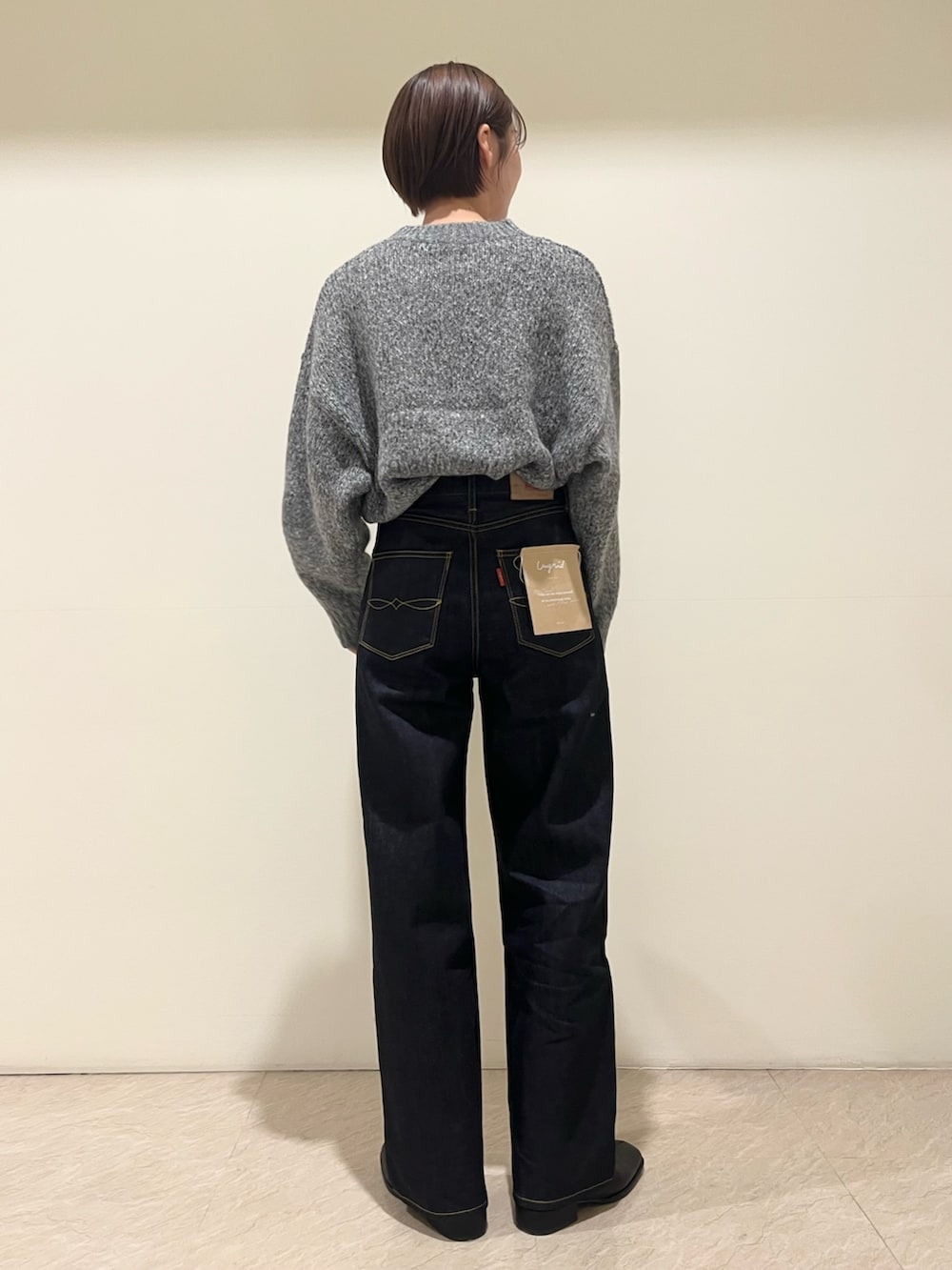 グレー系のニット/セーター、ブルー系のデニムパンツを着用したレディースの秋コーディネートの3枚目の写真