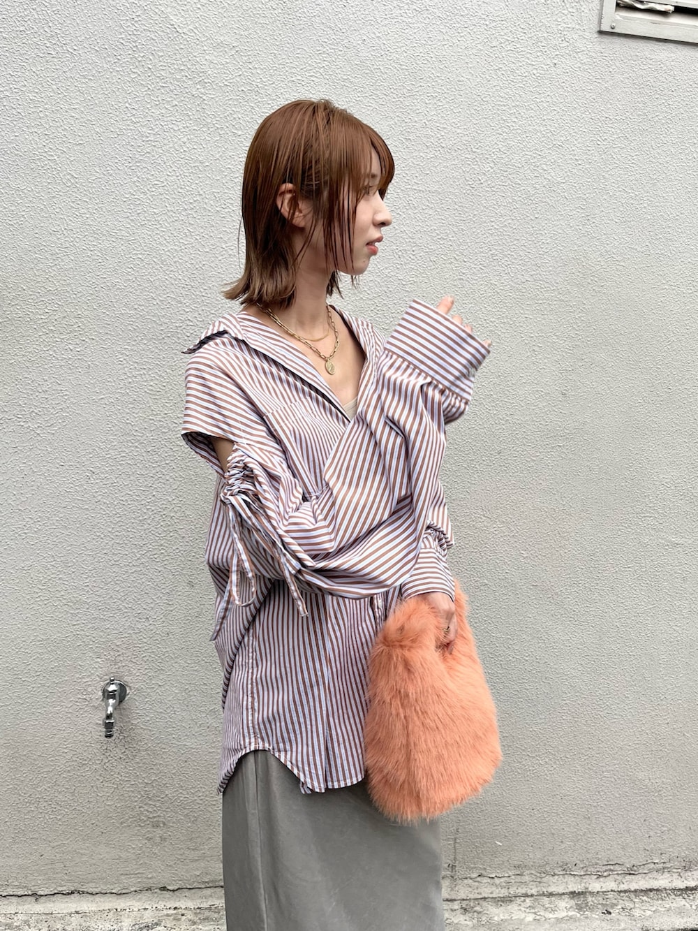 オレンジ系のハンドバッグ、ブラウン系のシャツ/ブラウス、グレー系のスカートを着用したレディースの秋コーディネートの3枚目の写真