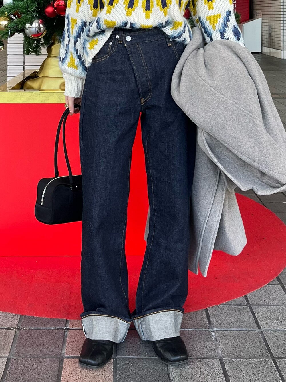 ホワイト系のニット/セーター、グレー系のチェスターコート、ブルー系のデニムパンツを着用したレディースの冬コーディネートの5枚目の写真