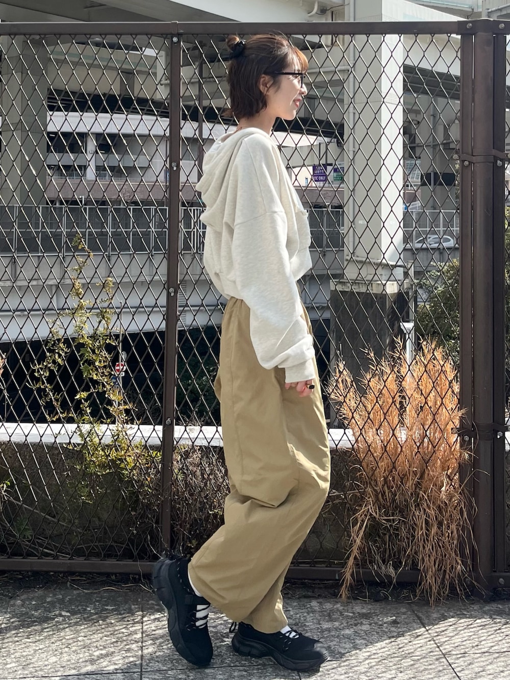 ホワイト系のパーカー、ベージュ系のその他パンツ、ブラック系のスニーカーを着用したレディースの春コーディネートの2枚目の写真