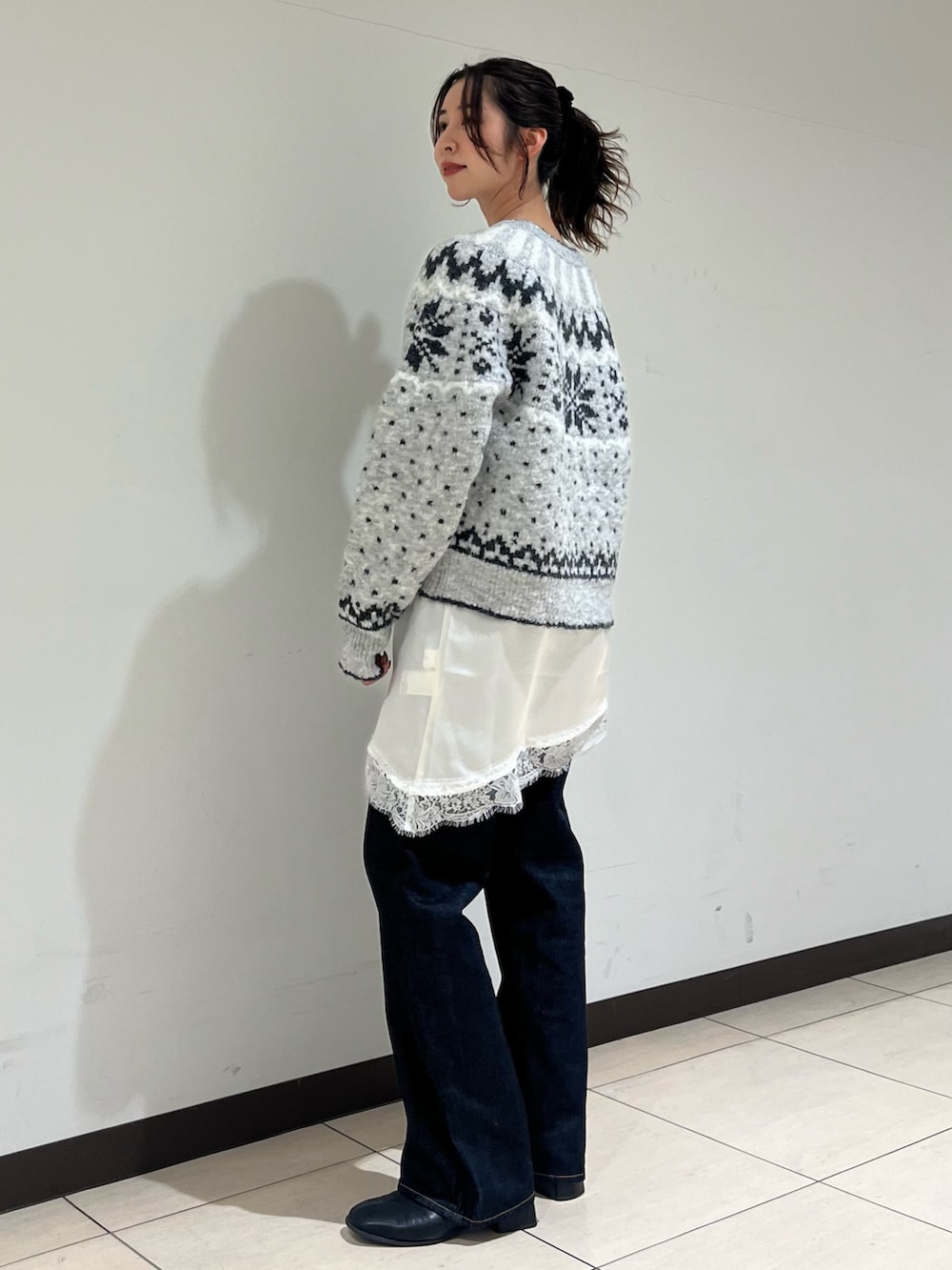 グレー系のニット/セーター、ホワイト系のキャミソール、ブルー系のデニムパンツを着用したレディースの冬コーディネートの2枚目の写真