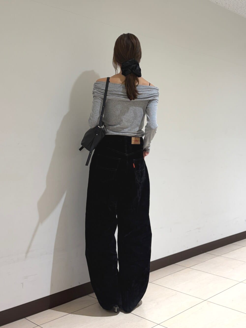 グレー系のTシャツ/カットソー、ブラック系のデニムパンツ、ブラック系のハンドバッグを着用したレディースの秋コーディネートの3枚目の写真