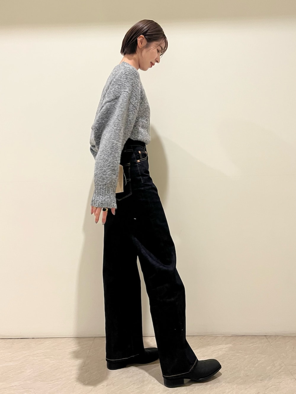 グレー系のニット/セーター、ブルー系のデニムパンツを着用したレディースの秋コーディネートの2枚目の写真