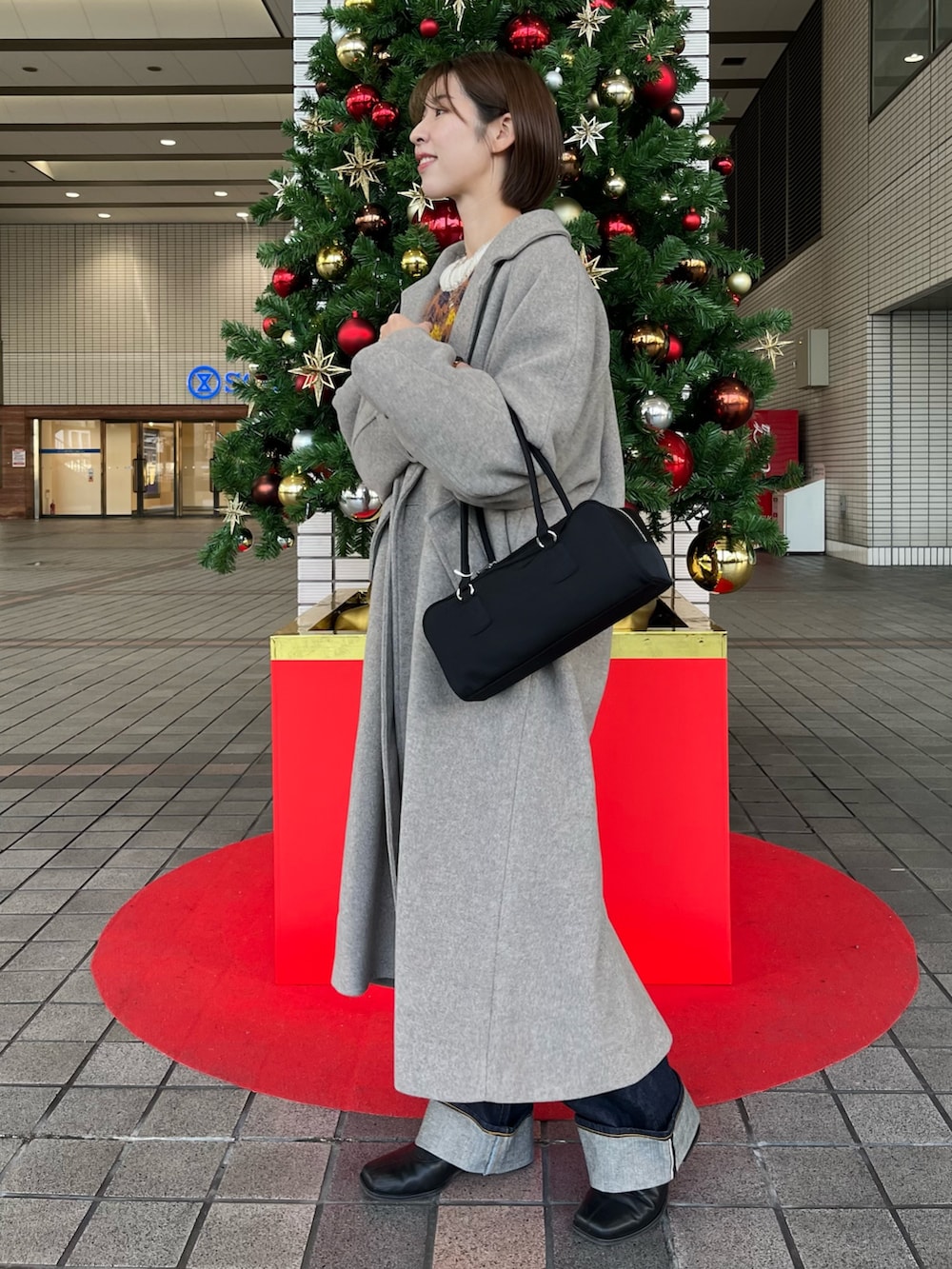 ホワイト系のニット/セーター、グレー系のチェスターコート、ブルー系のデニムパンツを着用したレディースの冬コーディネートの2枚目の写真