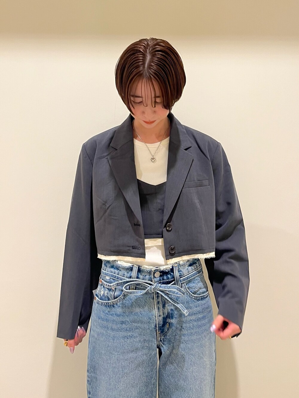 グレー系のテーラードジャケット、グレー系のキャミソール、ブルー系のデニムパンツを着用したレディースの夏コーディネートの4枚目の写真