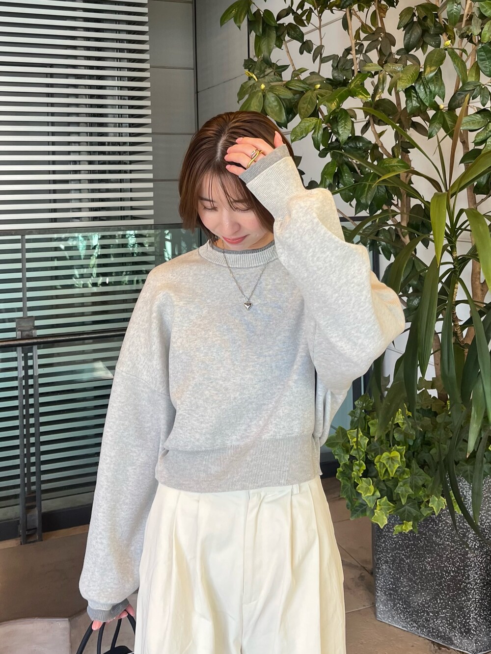 グレー系のニット/セーター、ホワイト系のチノパンツ、ブラック系のボストンバッグを着用したレディースの冬コーディネートの4枚目の写真