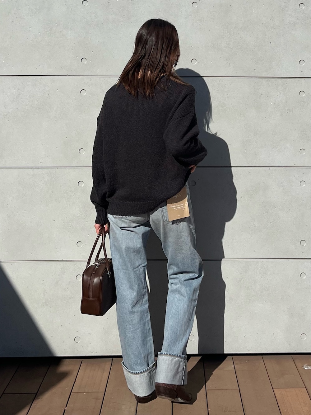 グレー系のニット/セーター、ブルー系のデニムパンツ、ブラウン系のハンドバッグを着用したレディースの冬コーディネートの3枚目の写真