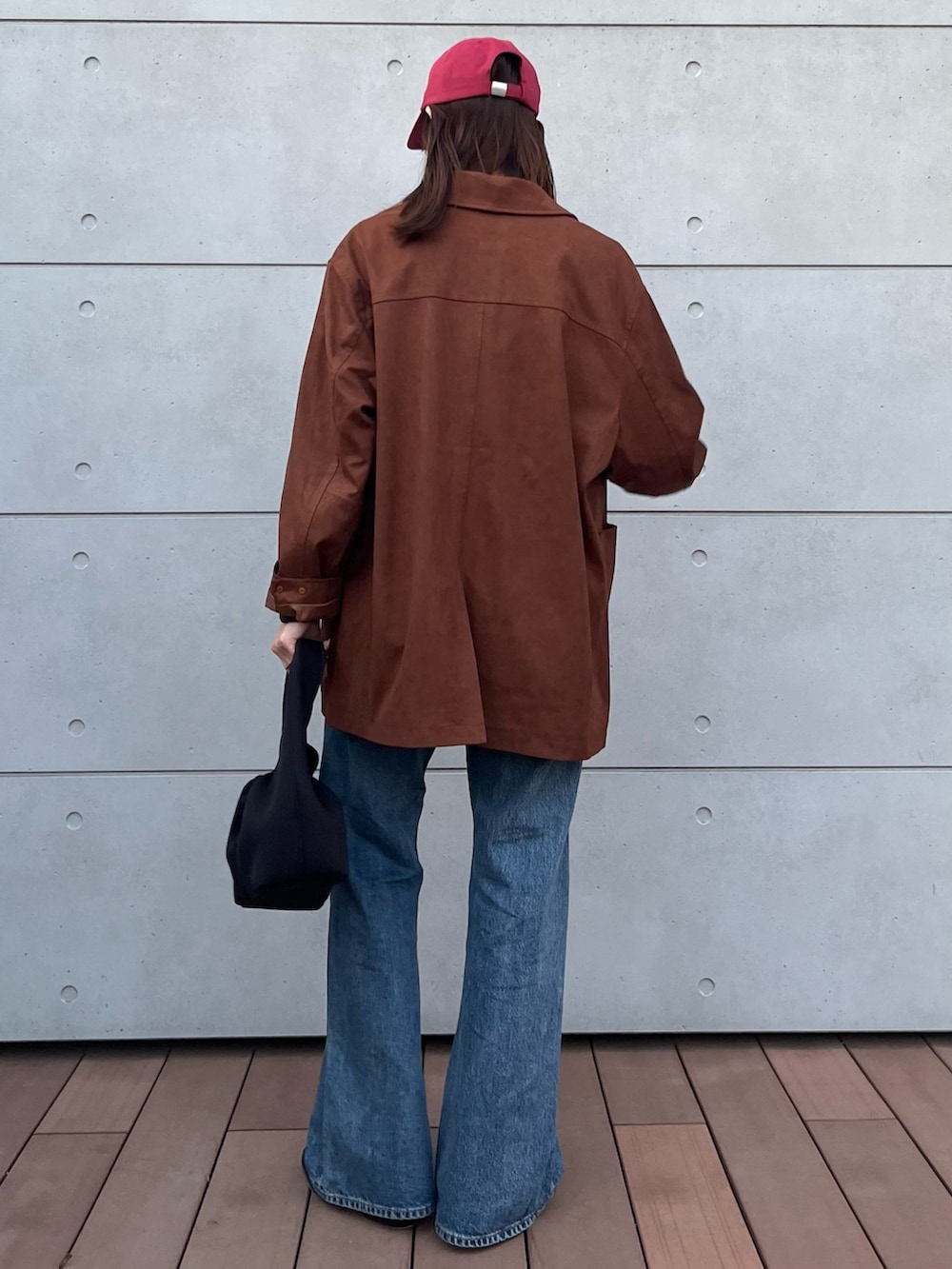 グレー系のTシャツ/カットソー、ブルー系のデニムパンツ、ブラック系のハンドバッグを着用したレディースの冬コーディネートの4枚目の写真