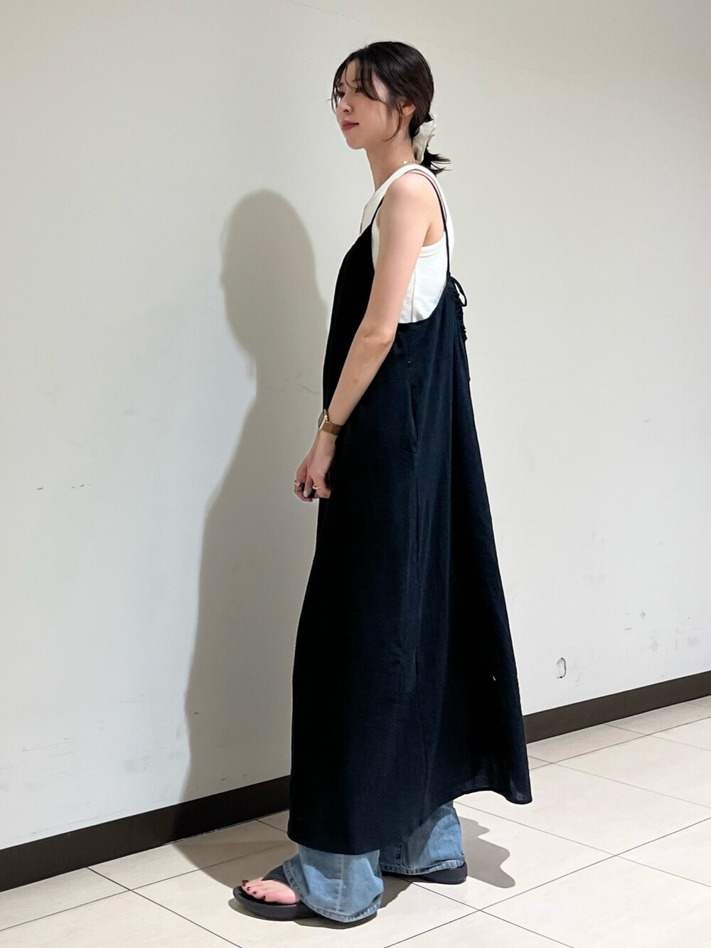 ブラック系のワンピース、ブルー系のデニムパンツを着用したレディースの夏コーディネートの2枚目の写真