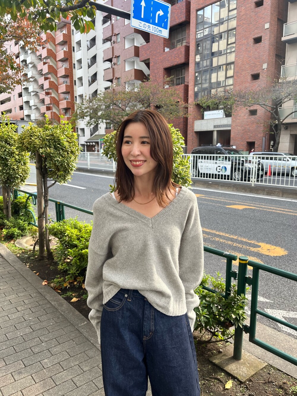 グレー系のニット/セーター、ブルー系のデニムパンツを着用したレディースの秋コーディネートの4枚目の写真