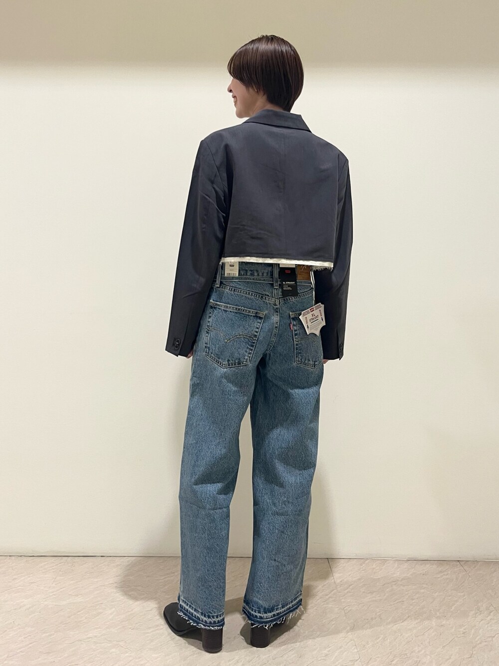 グレー系のテーラードジャケット、グレー系のキャミソール、ブルー系のデニムパンツを着用したレディースの夏コーディネートの3枚目の写真