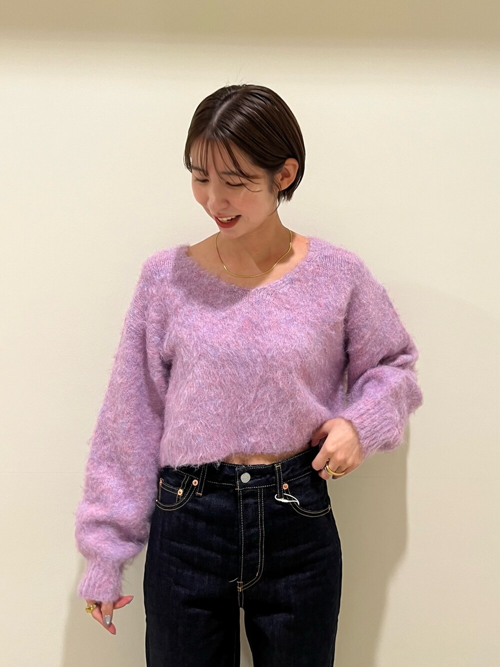 パープル系のニット/セーター、ブルー系のデニムパンツを着用したレディースの秋コーディネートの4枚目の写真