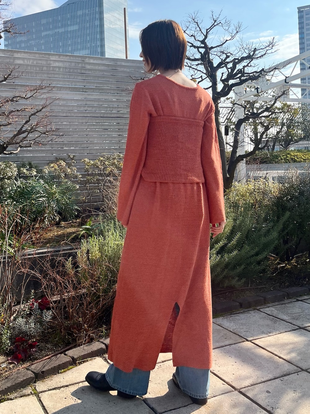 オレンジ系のワンピース、ブルー系のデニムパンツを着用したレディースの冬コーディネートの3枚目の写真