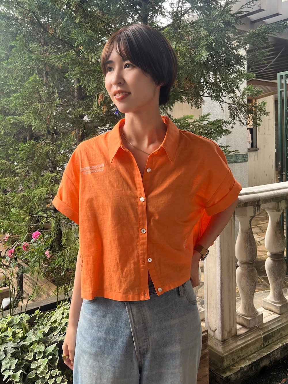 オレンジ系のシャツ/ブラウス、ブルー系のデニムパンツを着用したレディースの夏コーディネートの4枚目の写真