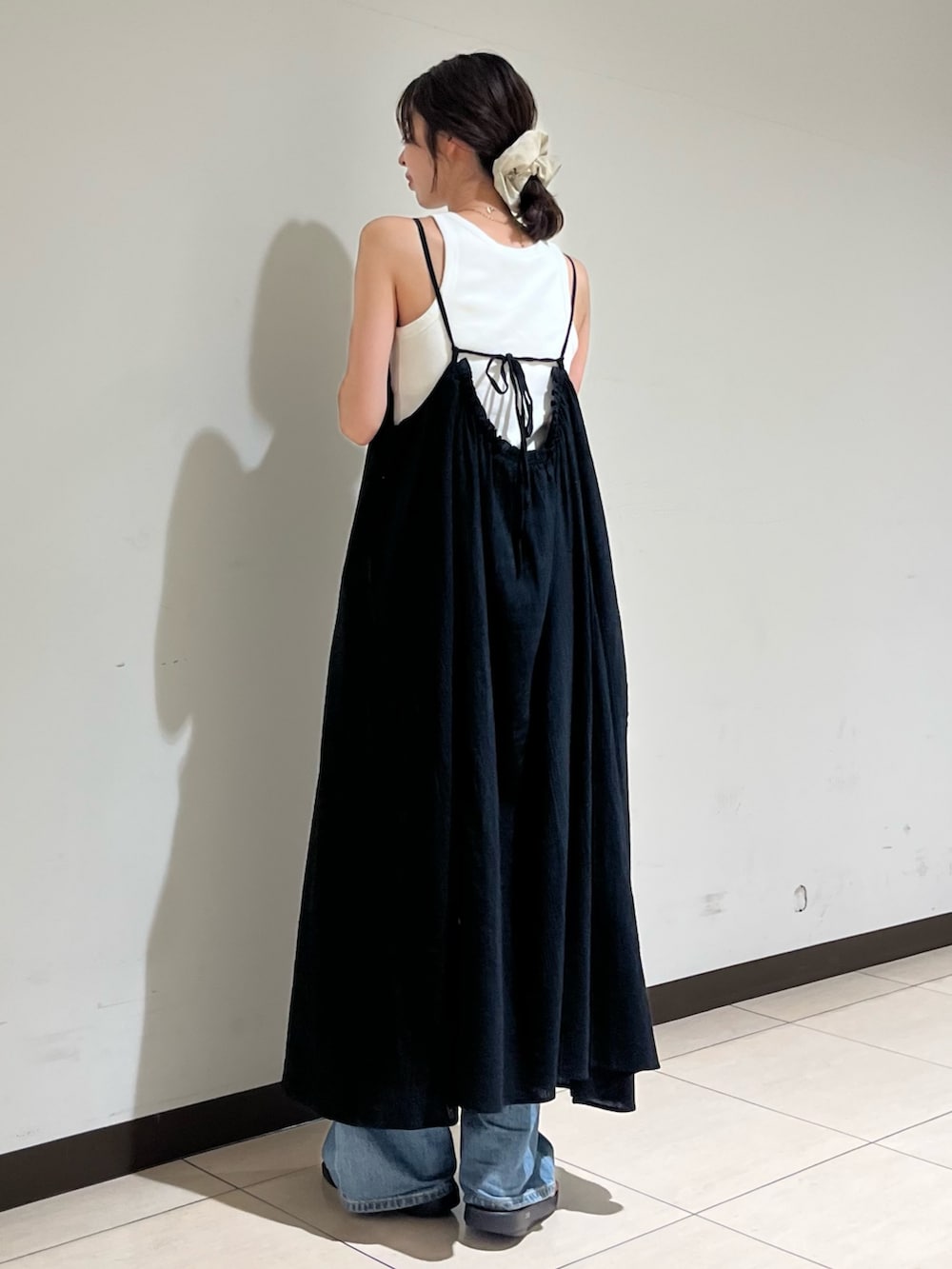 ブラック系のワンピース、ブルー系のデニムパンツを着用したレディースの夏コーディネートの3枚目の写真