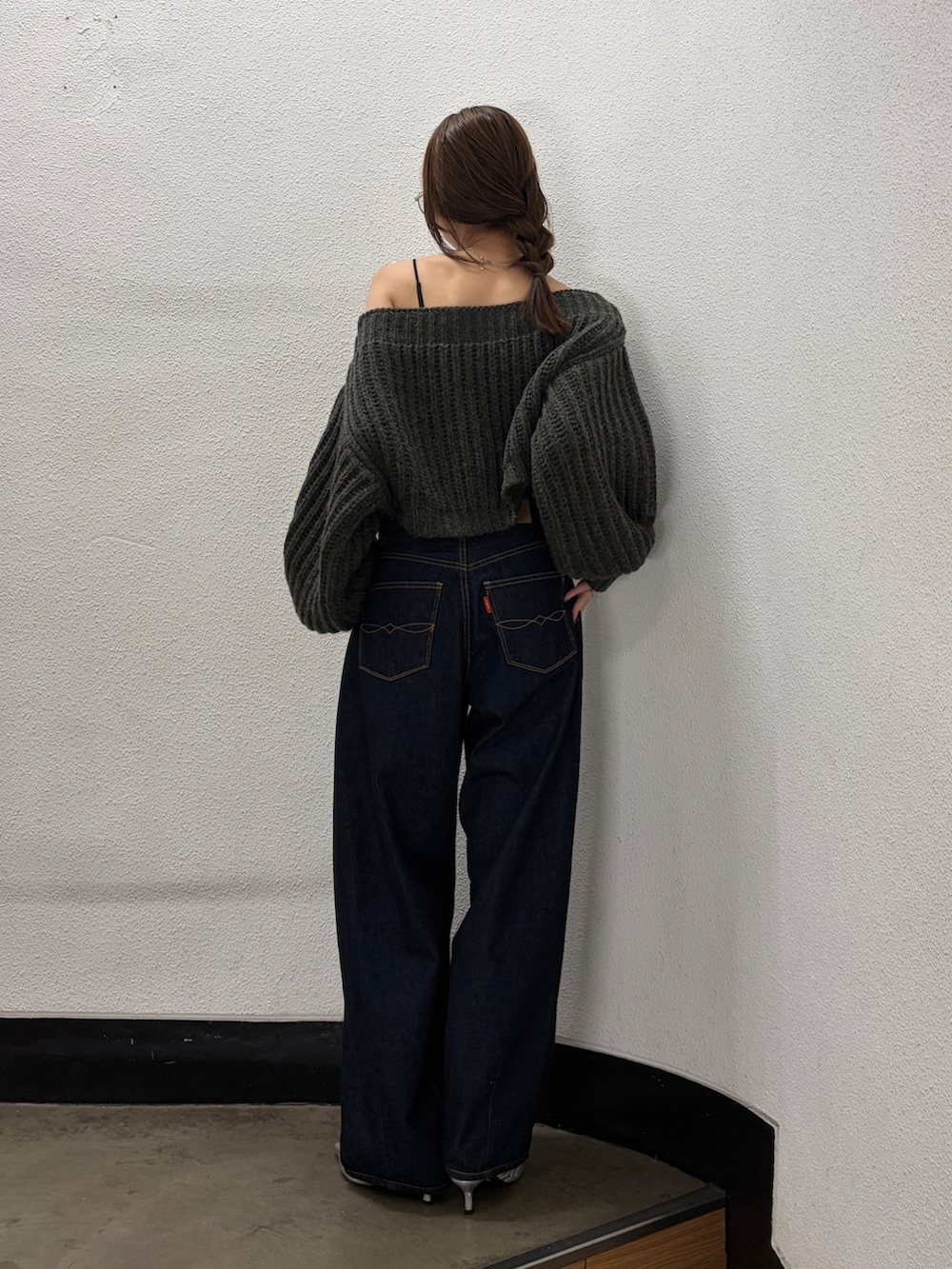 グレー系のニット/セーター、ブルー系のデニムパンツ、シルバー系のパンプスを着用したレディースの秋コーディネートの3枚目の写真