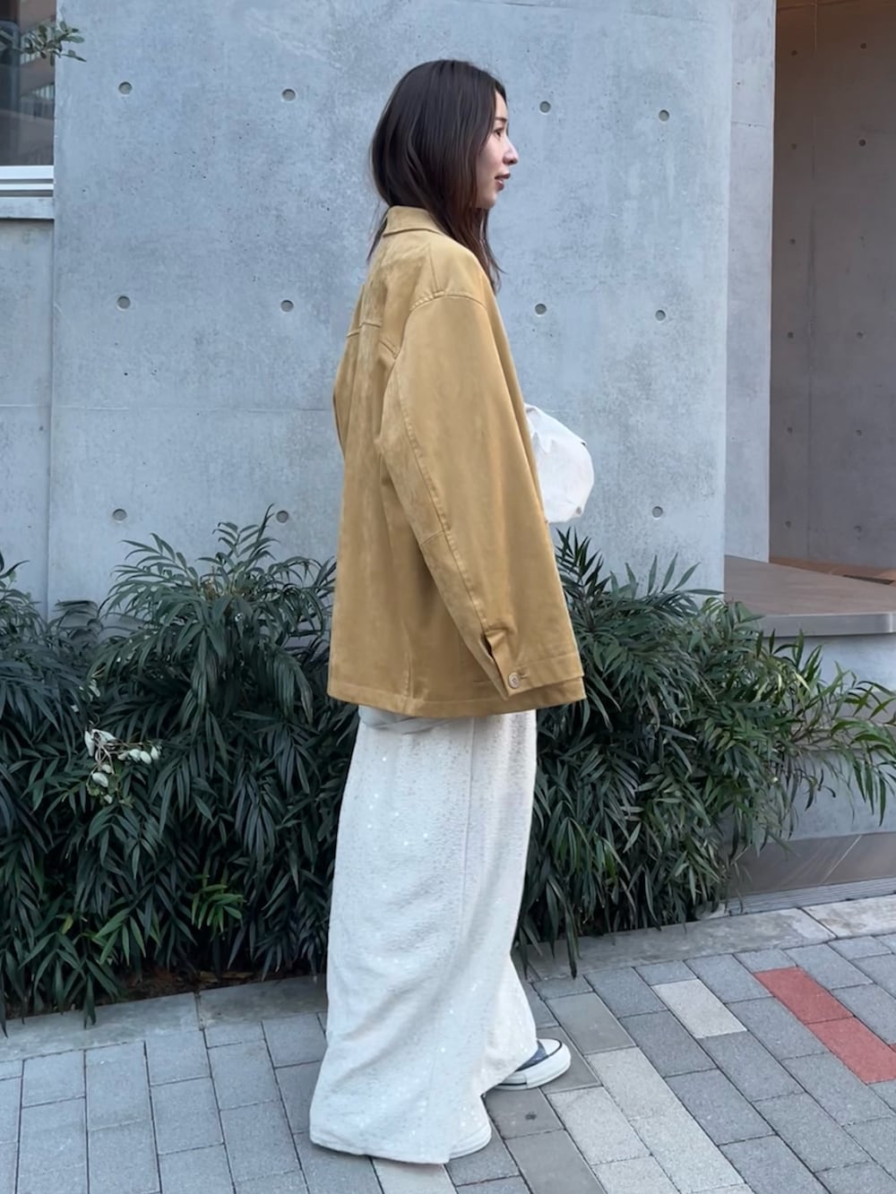 イエロー系のテーラードジャケット、グレー系のTシャツ/カットソー、ホワイト系のスカートを着用したレディースの冬コーディネートの2枚目の写真