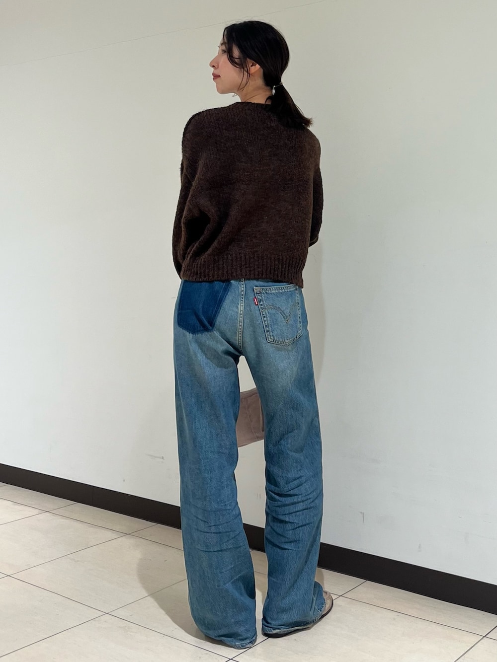 ブラウン系のニット/セーター、ブルー系のデニムパンツ、ピンク系のハンドバッグを着用したレディースの秋コーディネートの3枚目の写真