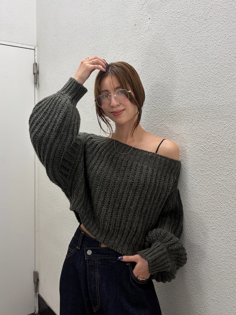 グレー系のニット/セーター、ブルー系のデニムパンツ、シルバー系のパンプスを着用したレディースの秋コーディネートの4枚目の写真