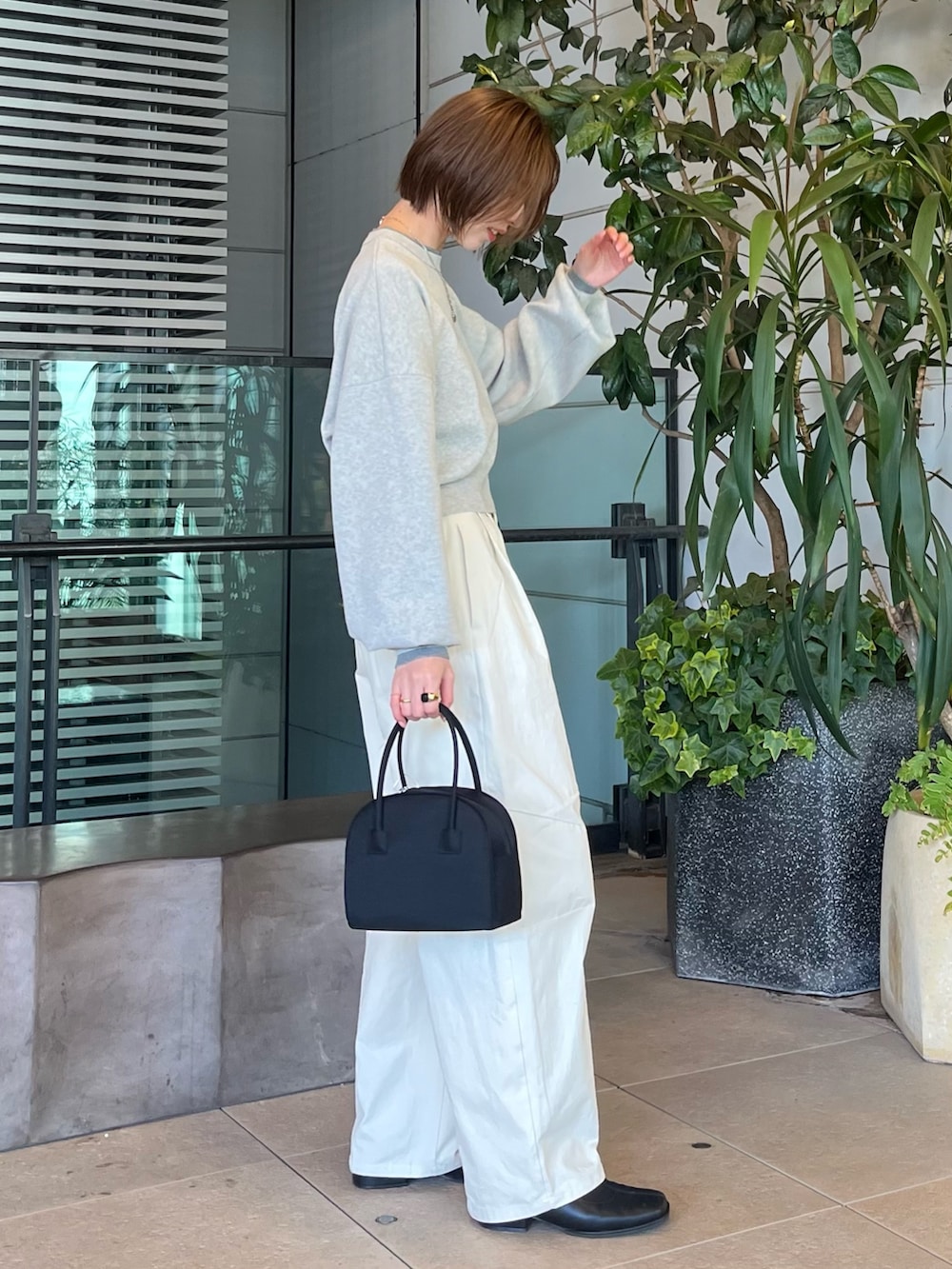 グレー系のニット/セーター、ホワイト系のチノパンツ、ブラック系のボストンバッグを着用したレディースの冬コーディネートの2枚目の写真