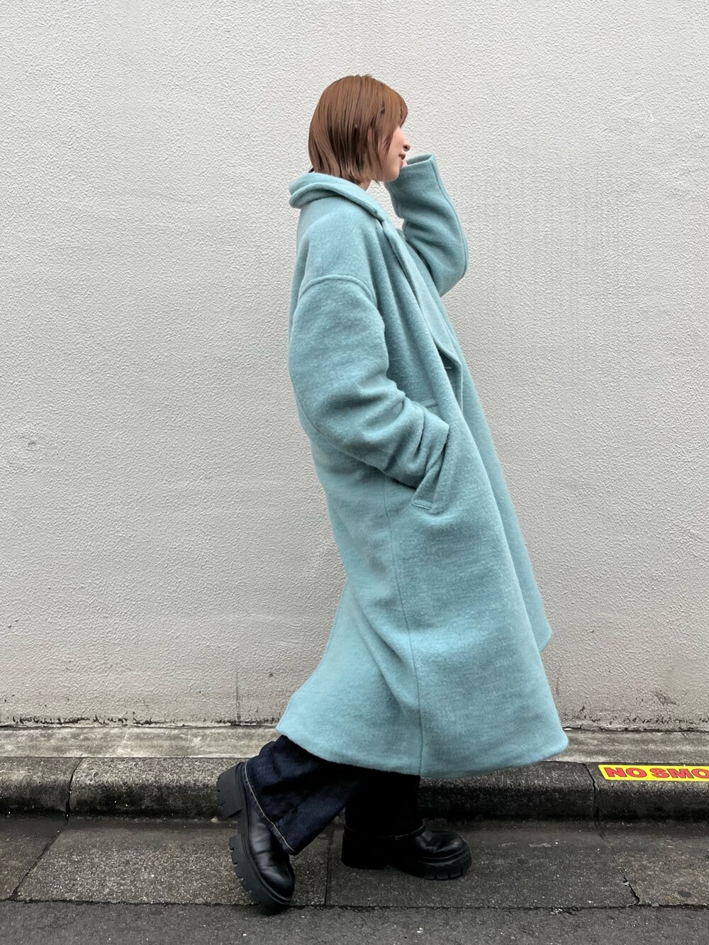 ブルー系のチェスターコート、ホワイト系のニット/セーター、ブルー系のデニムパンツを着用したレディースの秋コーディネートの3枚目の写真