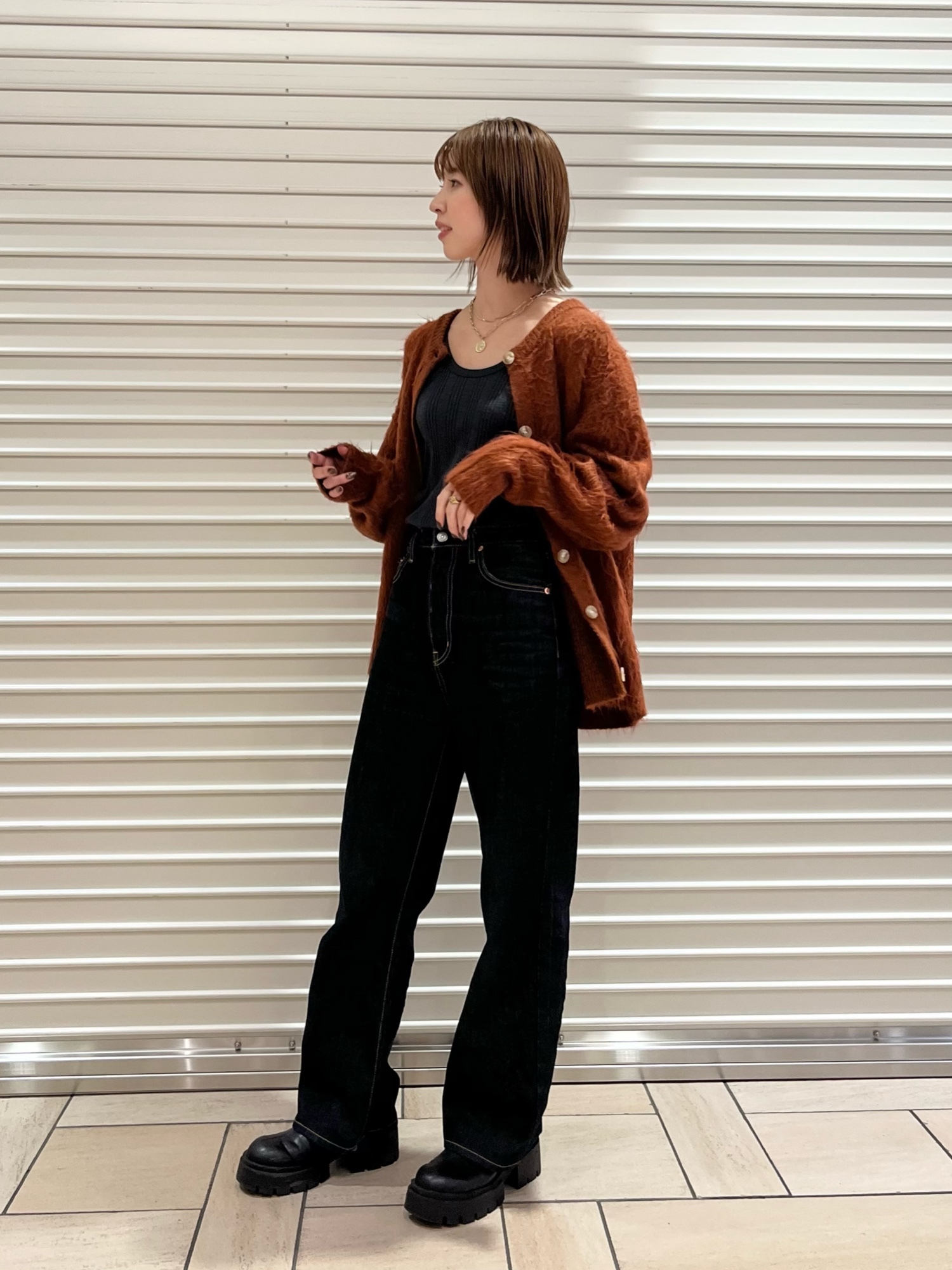 グレー系のTシャツ/カットソー、オレンジ系のカーディガン/ボレロ、ブルー系のデニムパンツを着用したレディースの秋コーディネートの2枚目の写真