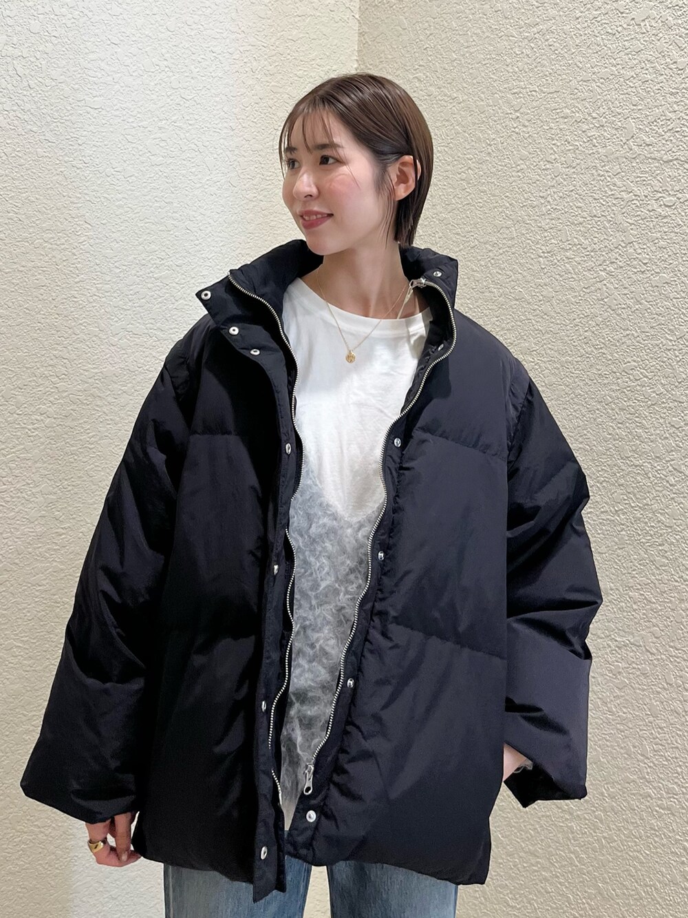 ブラック系のダウンジャケット/コート、ホワイト系のTシャツ/カットソー、グレー系のニット/セーターを着用したレディースの冬コーディネートの4枚目の写真