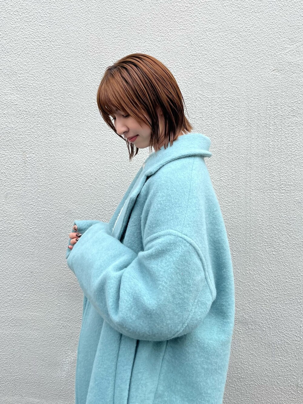 ブルー系のチェスターコート、ホワイト系のニット/セーター、ブルー系のデニムパンツを着用したレディースの秋コーディネートの5枚目の写真