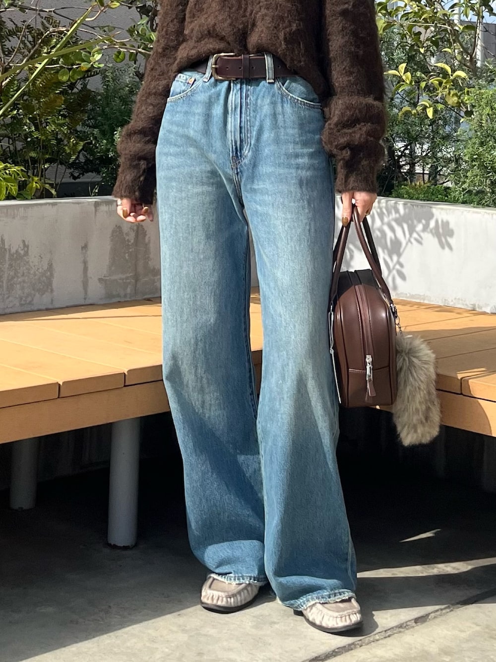 ブラウン系のニット/セーター、ブルー系のデニムパンツ、ブラウン系のハンドバッグを着用したレディースの秋コーディネートの6枚目の写真