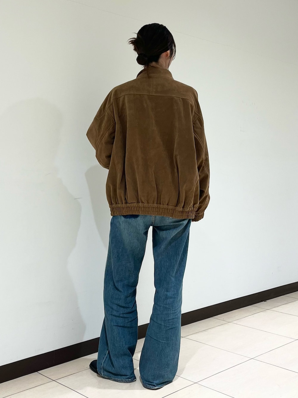 ブルー系のデニムパンツ、ブラウン系のブルゾンを着用したレディースの秋コーディネートの3枚目の写真