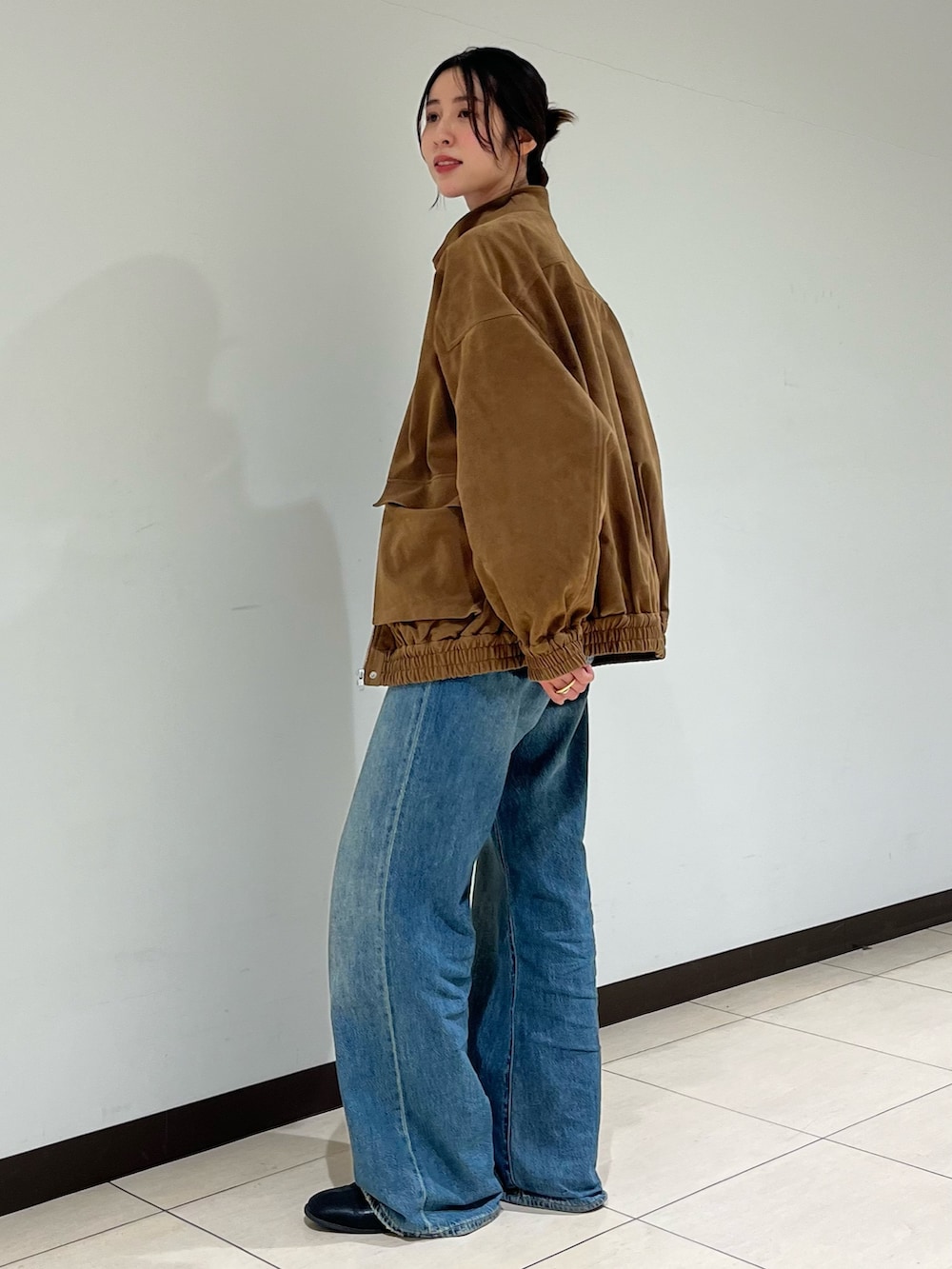 ブルー系のデニムパンツ、ブラウン系のブルゾンを着用したレディースの秋コーディネートの2枚目の写真