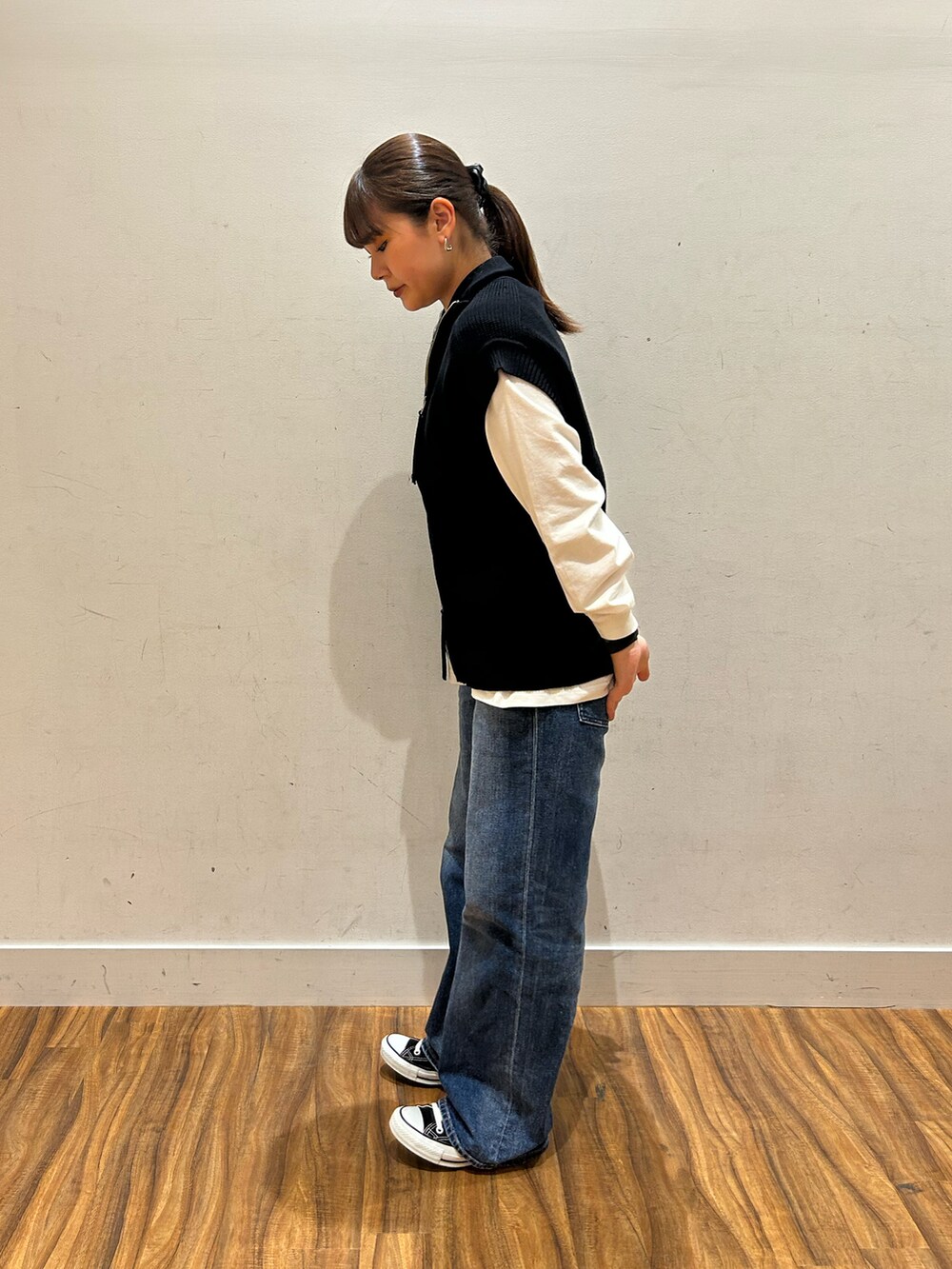 ブルー系のデニムパンツ、ブラック系のベストを着用したレディースの秋コーディネートの2枚目の写真